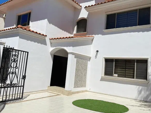 Casa blanca con jardín y entrada.